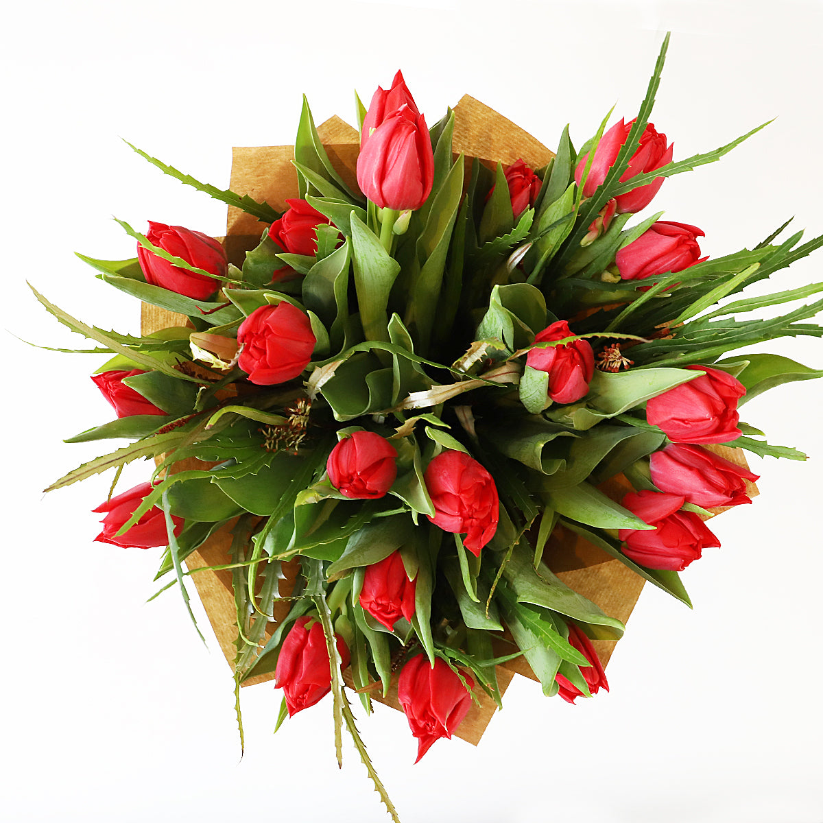 Overhead view of a bouquet of red tulip and foliage wrapped in brown paper