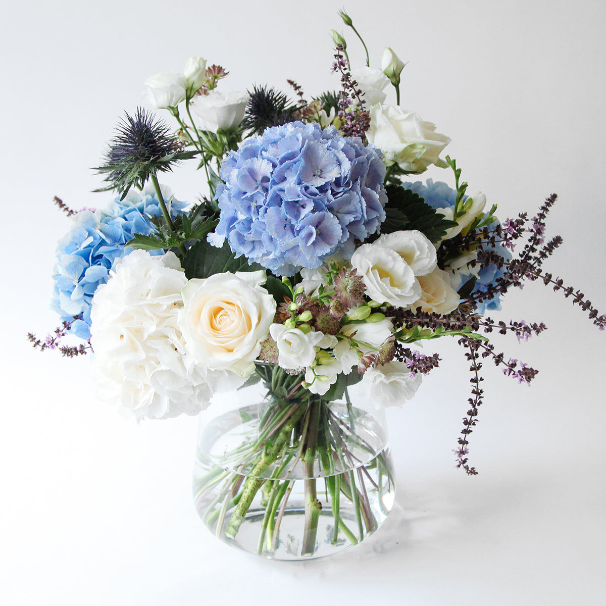 Vase of blue and white hydrangeas, thistle and white lisianthus