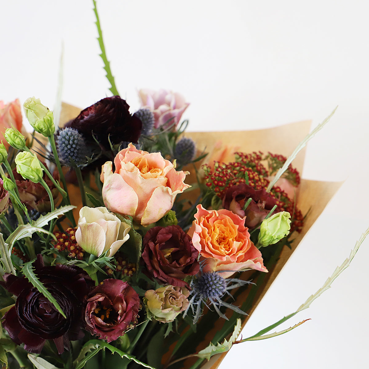 Detail view of orange rosees, thistle and burgundy flowers