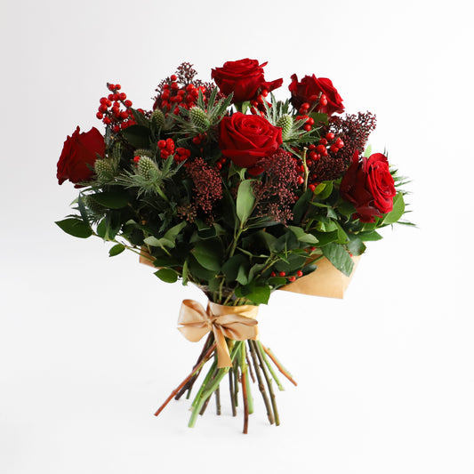 A six red rose bouquet with thistle, ilex berries and seasonal foliage