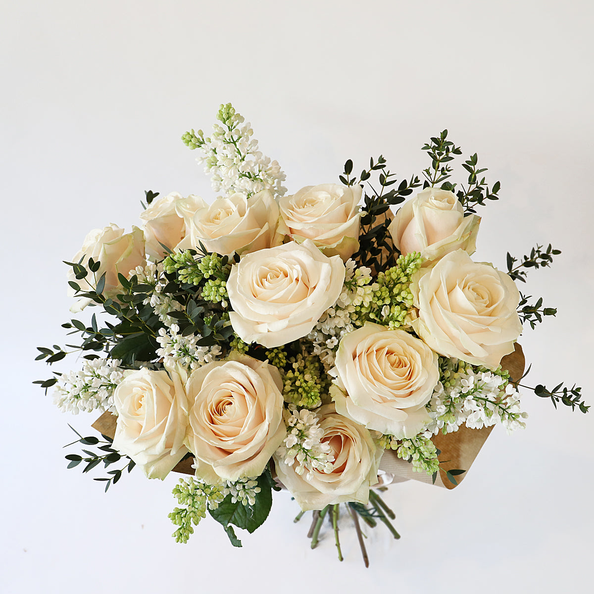 Overhead shot of cream roses, white lilac and eucalyptus bouquet