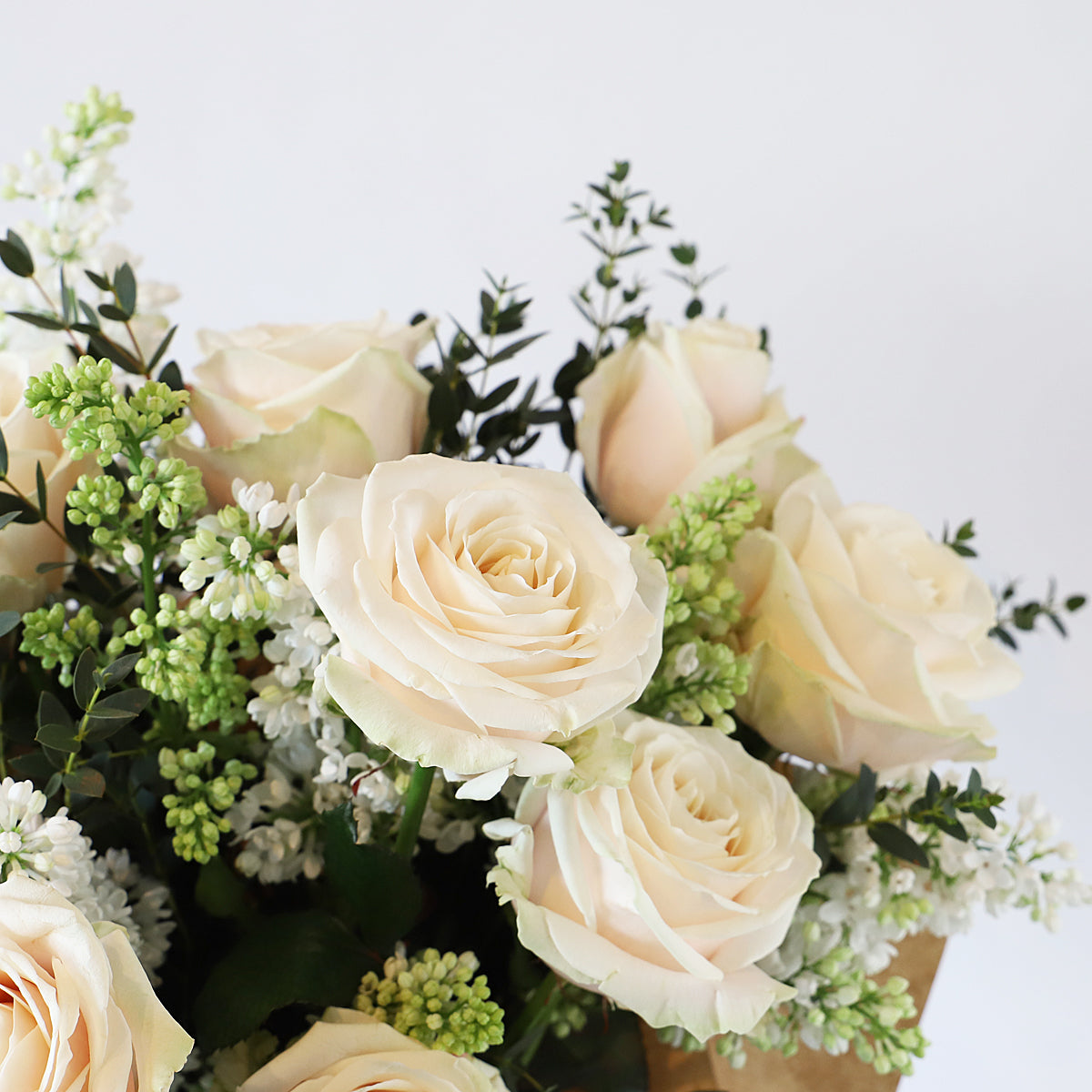 A detail close up of cream roses, white lilac and eucalyptus