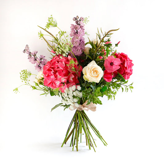 A large bouquet of pink hydrangeas, cream roses, lilac delphinium, pink lavateria and soft white ami