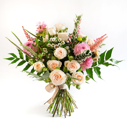 A large bouqeut with cream spray roses, pink astibe, pink dahlia, wax flower and foliage