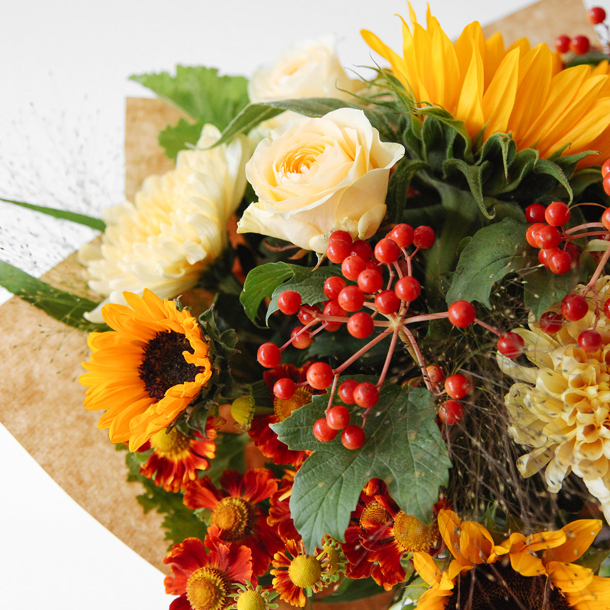 Detail view of sunflowers, yellow roses, blooms and seasonal foliages