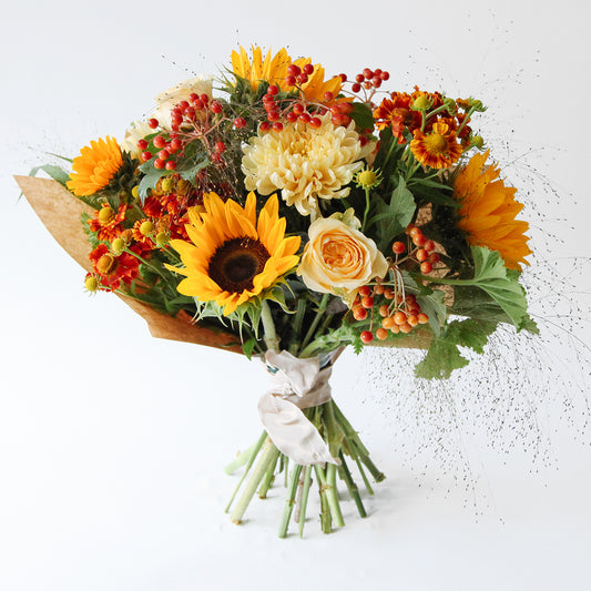 Bouquet with sunflowers, blooms, yellow roses and seasonal foliage