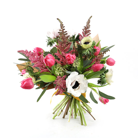 A bouquet containing pink tulips, white anemones, pink astilbe and pink veronica