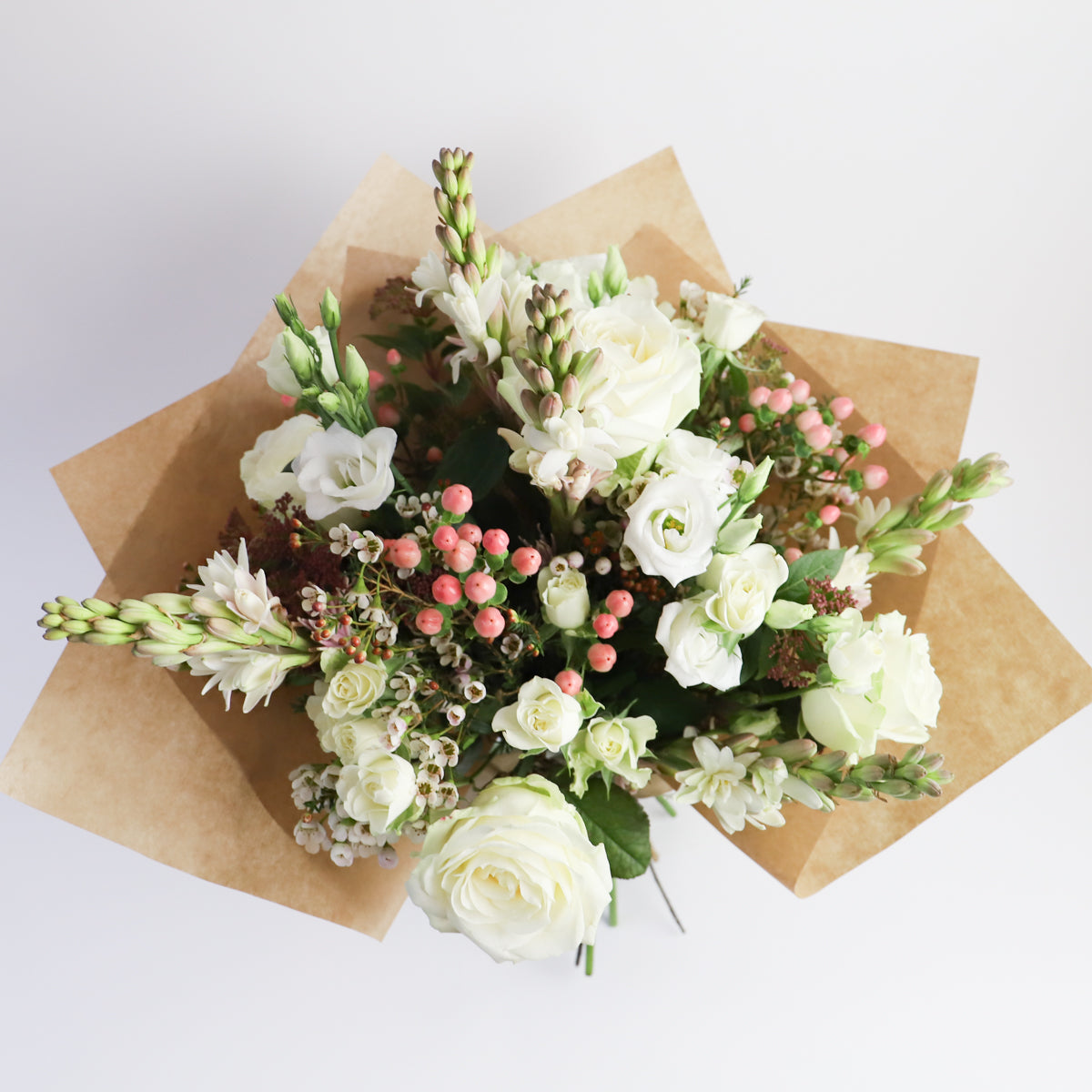 Over head view of white roses, pink hypericum and tuberose