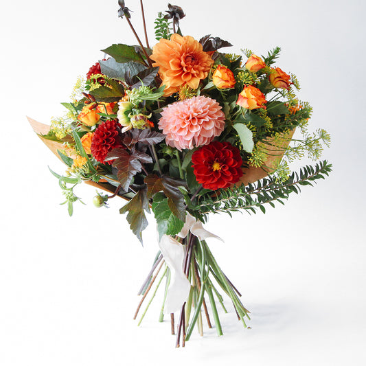 Bouquet with orange, red and coral dahlias, orange roses and seasonal foliages