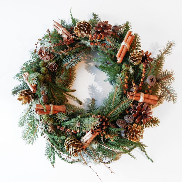 Christmas wreath with pine cones, cinnamon sticks, and evergreen branches on a white background