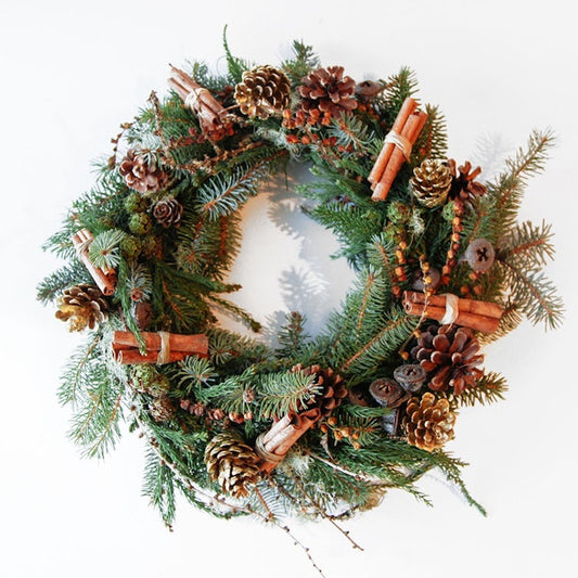 Christmas wreath with pine cones, cinnamon sticks, and evergreen branches on a white background